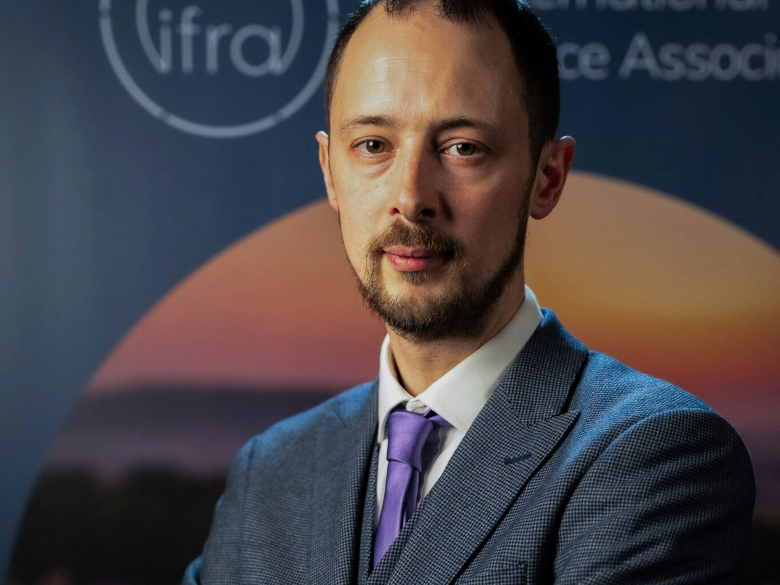 Участник мероприятия на фоне логотипа IFRA